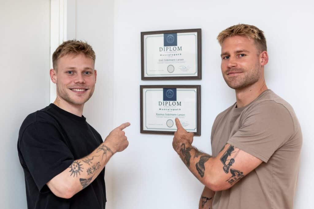 Emil og Rasmus, RAB-registrerede behandlere, ved deres diplomer i klinikken hos CORE